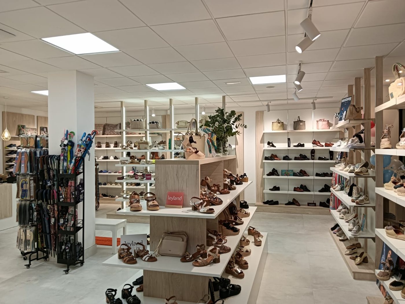 Interior de la tienda con mostrador central de sandalias y estanterías de bolsos al fondo