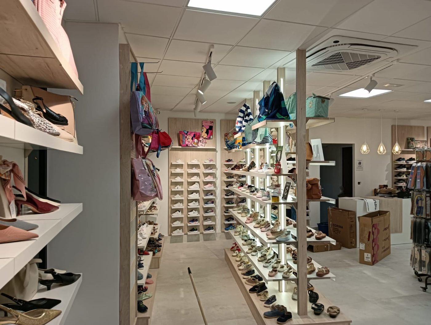 Sección infantil con zapatillas en la pared y expositor de calzado