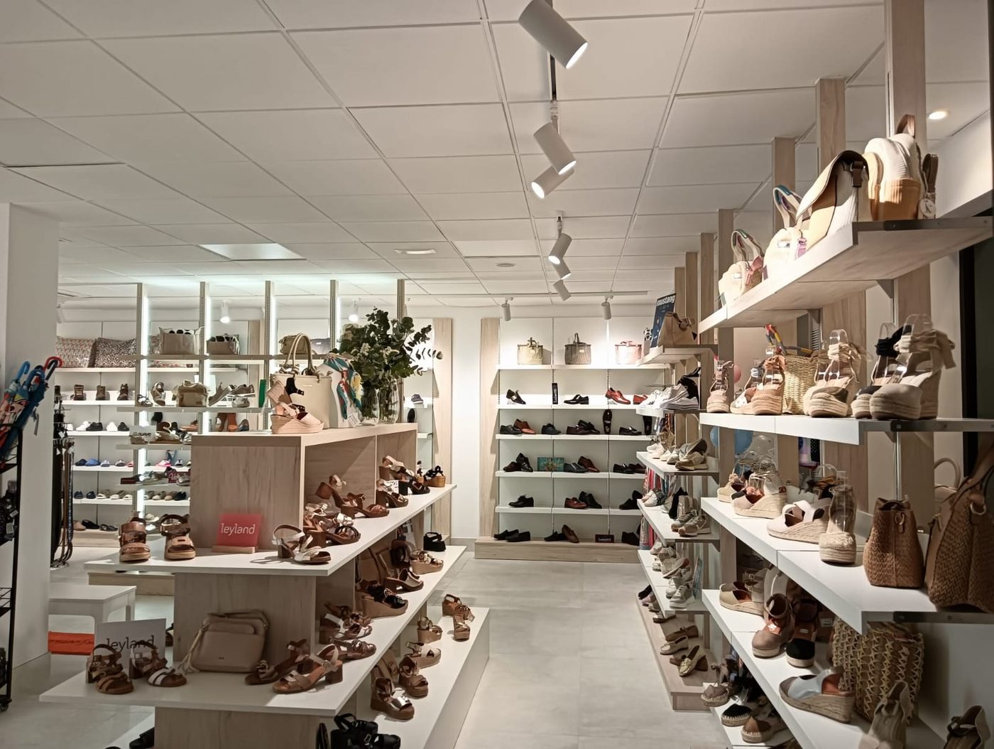 Pasillo de la tienda con expositor de calzado y bolsos a la derecha